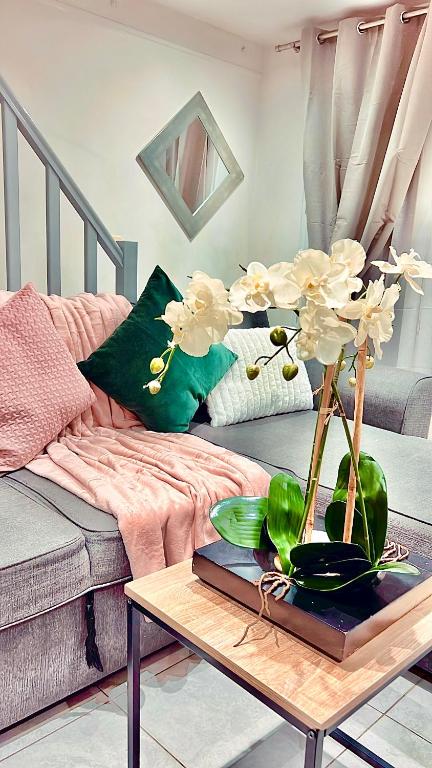 un salon avec un canapé et une table avec des fleurs dans l'établissement Fabulous apartment Air conditioned Nice Terrace 10 min from Paris, à Vitry-sur-Seine