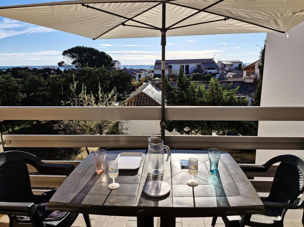 - une table avec des verres et un parasol sur le balcon dans l'établissement Résidence Le Carlton - 2 Pièces 4 couchages PORT LEUCATE. Réf: 2CAR_218C MAE-5171, à Leucate
