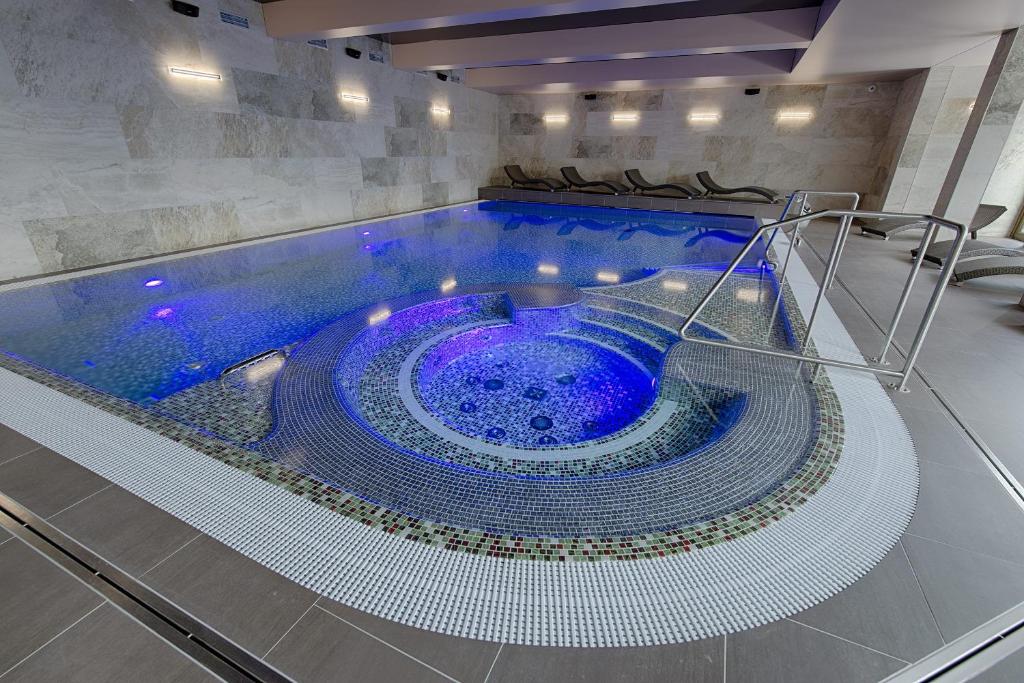 a large pool with a blue tub in a building at Hotel Orion in Abertamy