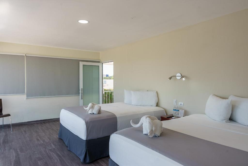Una habitación de hotel con dos camas con animales de peluche encima. en Hotel Windsor Plaza, en San Salvador