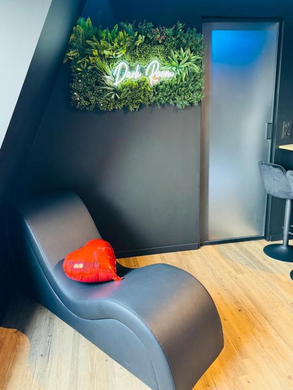 une chaise avec un oreiller rouge assis au sol dans l'établissement DARK ROOM - Suite Luxueuse près de la mer, à Villers-sur-Mer