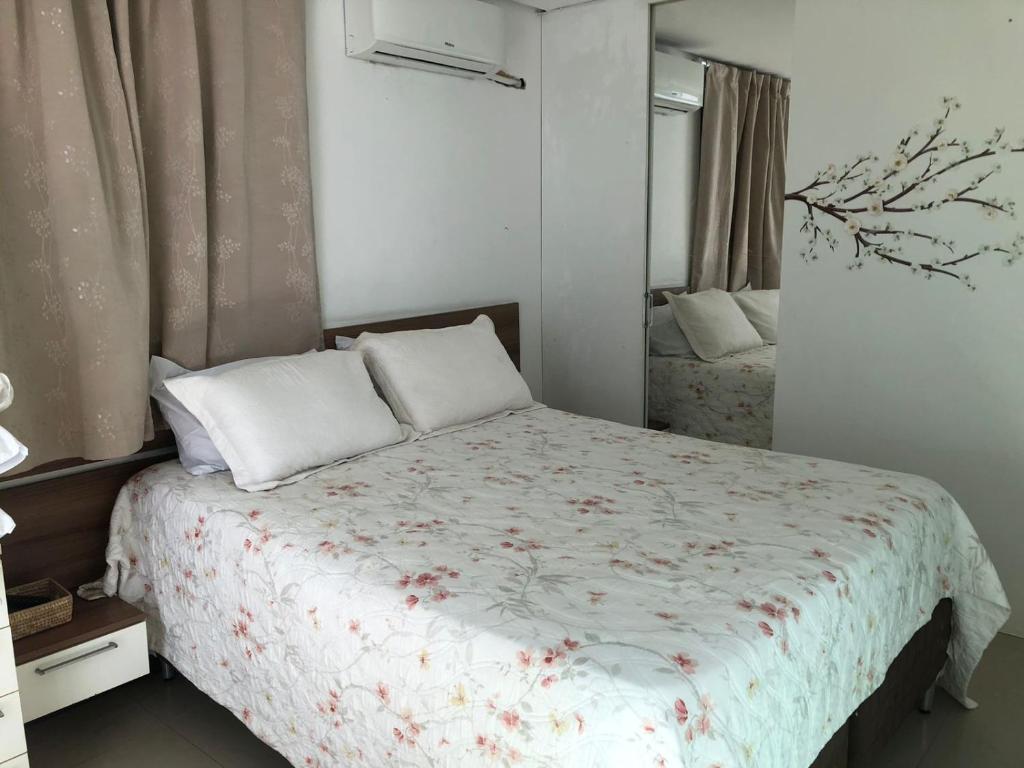 ein Schlafzimmer mit einem Bett mit geblümter Tagesdecke in der Unterkunft Praia do Flamengo 150m da praia Casa Ballalai in Salvador