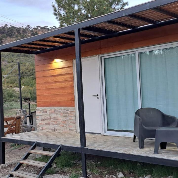 a house with a deck with a chair and a window at Monoambiente Neli in Villa Pehuenia