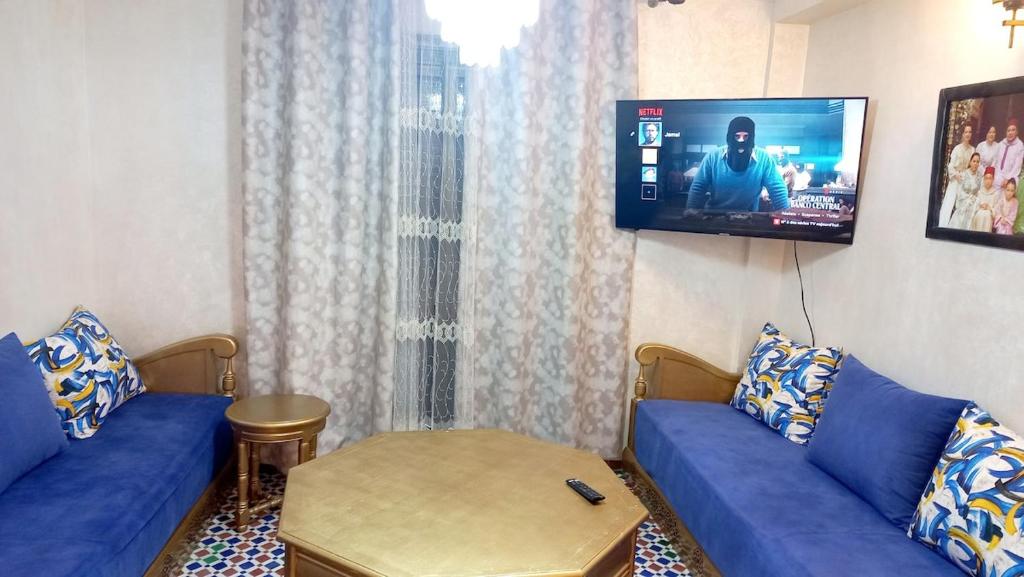 a living room with two blue couches and a flat screen tv at Charming Oasis in Marrakesh in Marrakech