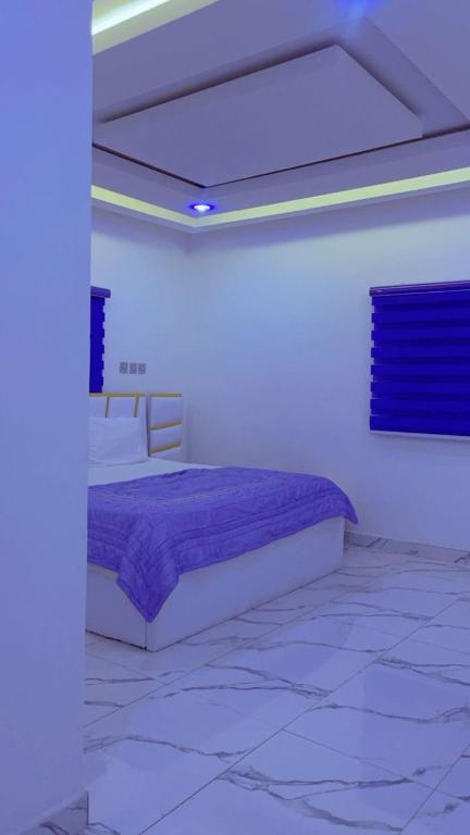 a bedroom with a bed with a purple blanket at Urban Shortlet Abuja in Abuja