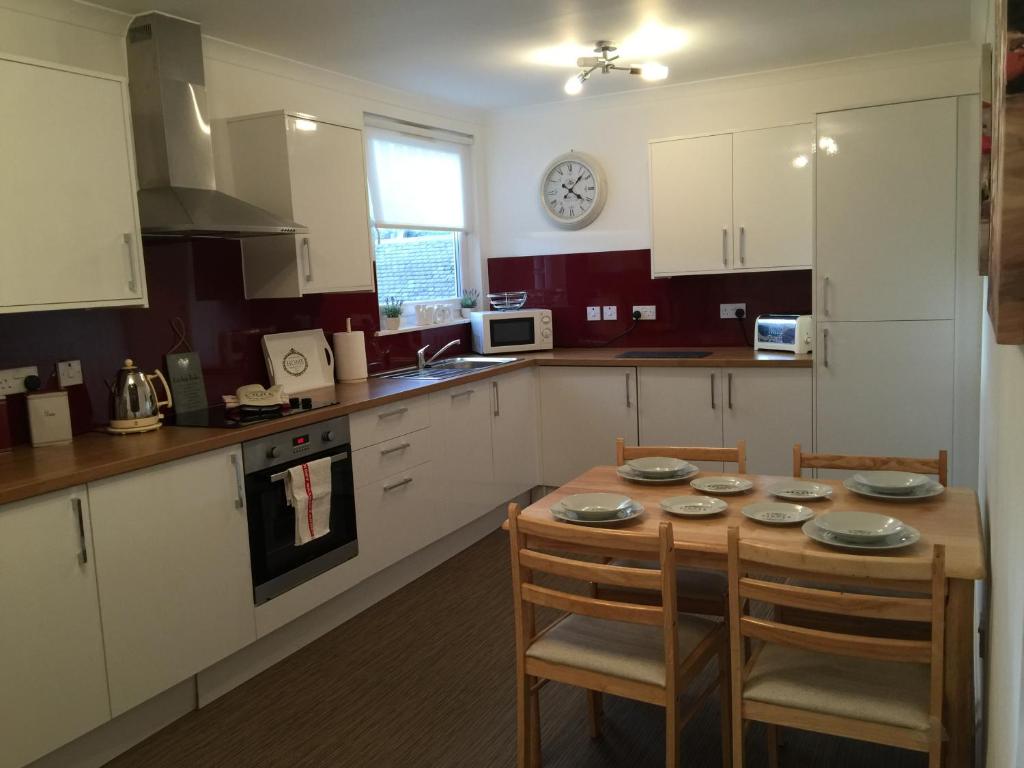 a kitchen with a table and chairs and a clock on the wall at North Bridge Apartment in Hawick