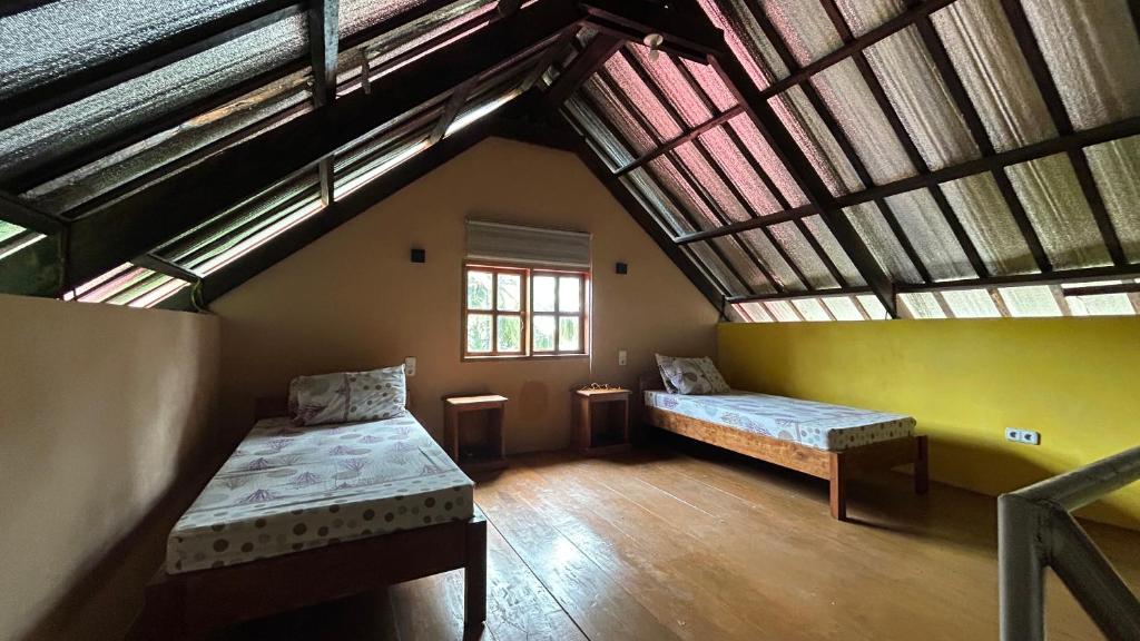 a attic room with two beds and a window at Strandhaus auf Sibuyan Island nahe Cresta de Gallo - Marevic's Guesthouse 2 in San Fernando