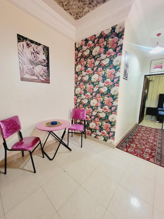 a room with two chairs and a table and a floral wall at Studio de luxe discret propre avec Wi-Fi in Yof