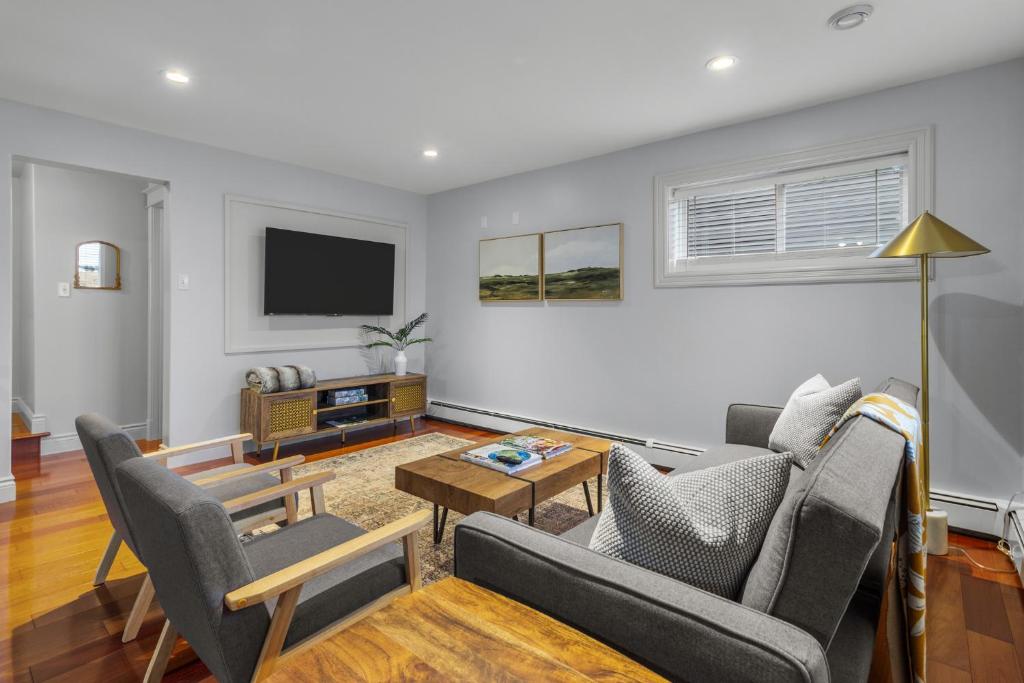 een woonkamer met een bank, stoelen en een tv bij Forest House 1 Bdrm Qv Lake View Parking in St. John's