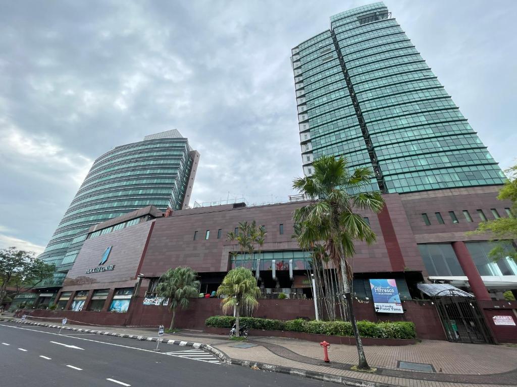a building with two tall buildings and palm trees at Hock Lee Hotel Residences - Anna 温馨公寓式的住宅 in Kuching