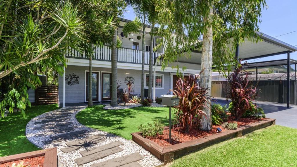 a house with palm trees in front of it at Family Holiday Perfection in Bellara