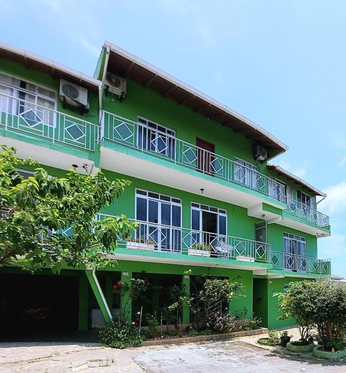 a green building with blue balconies on it at Pousada Altos dos Ingleses II in Florianópolis