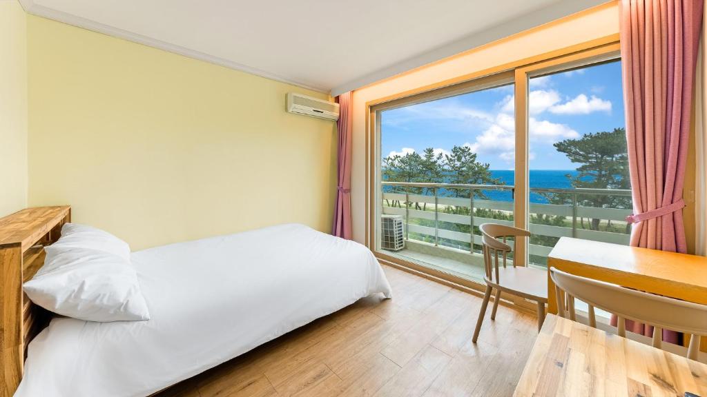 a bedroom with a bed and a desk and a window at Gangneng badapunggeong Pension in Gangneung