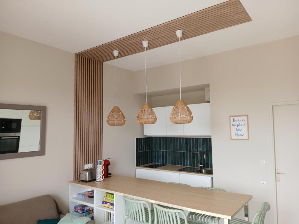 Eine Küche mit drei Pendelleuchten über der Arbeitsplatte in der Unterkunft Appart du golf in Saint-Jean-de-Monts
