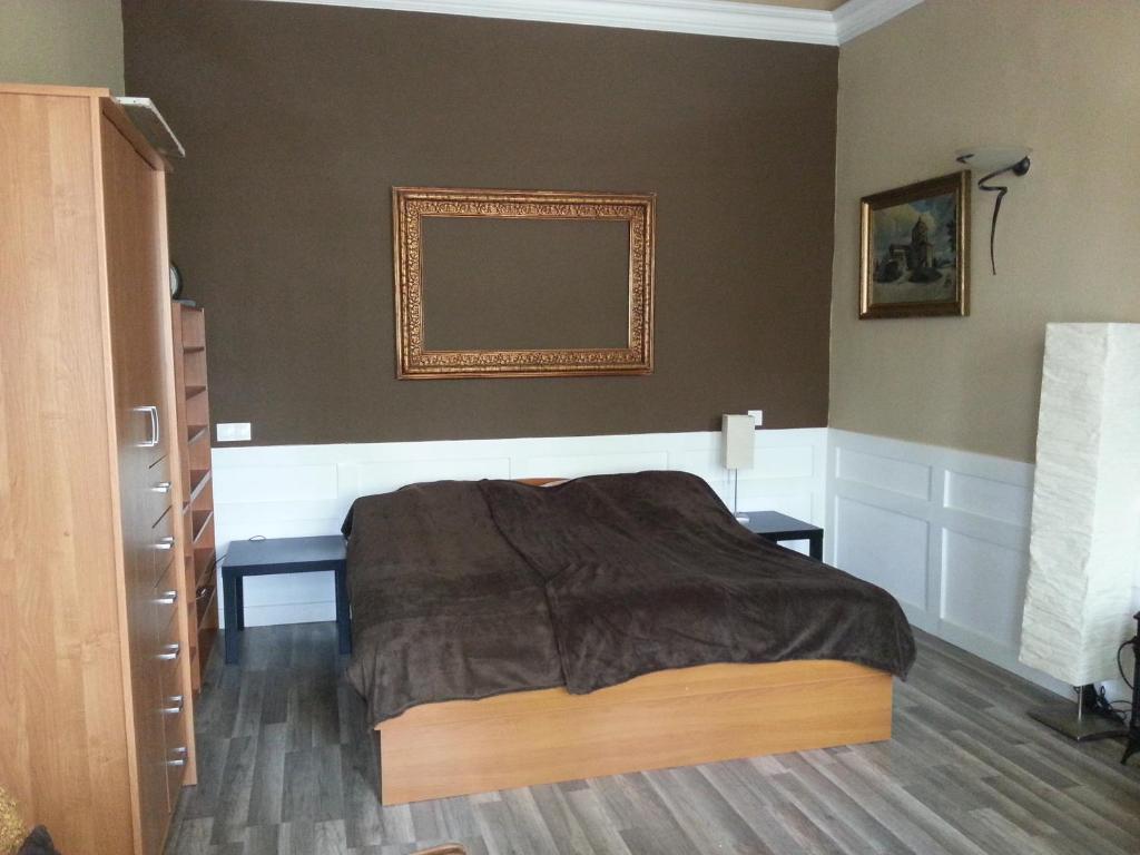 シオーフォクにあるNosztalgia apartmanのベッドルーム1室(ベッド1台付)が備わります。壁に絵が飾られています。