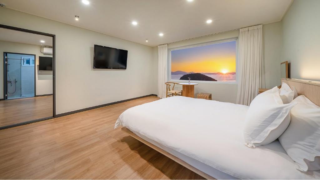 une chambre avec un grand lit et une grande fenêtre dans l'établissement Namhae U9Stay, à Namhae