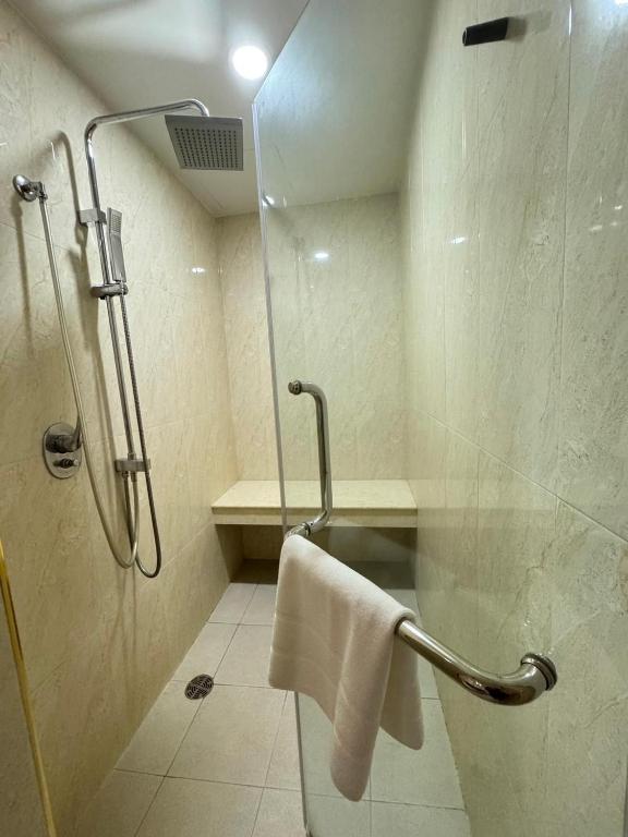A compact glass-screened shower room has a rainfall shower, handheld spray and built-in bench.