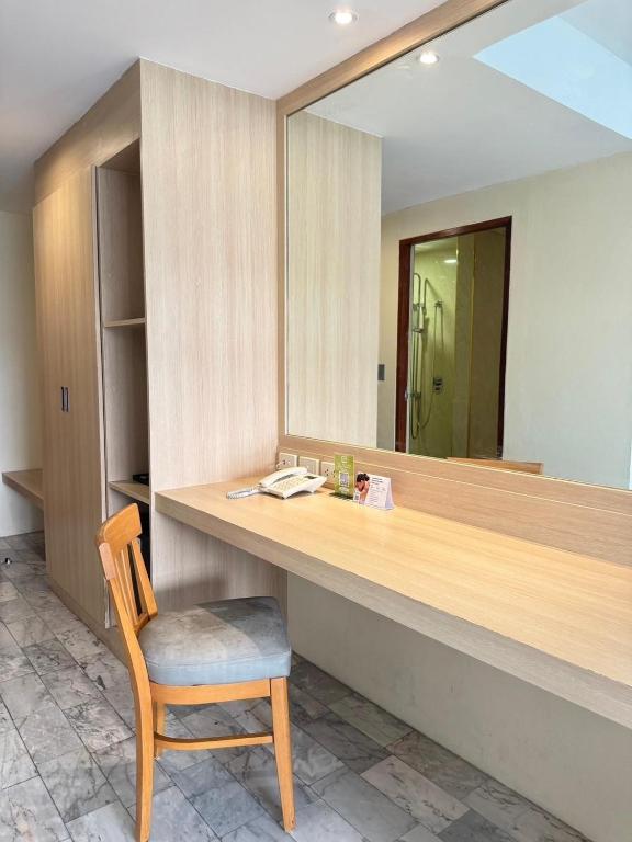 A compact in-room desk beneath a wide mirror beside the wardrobe.