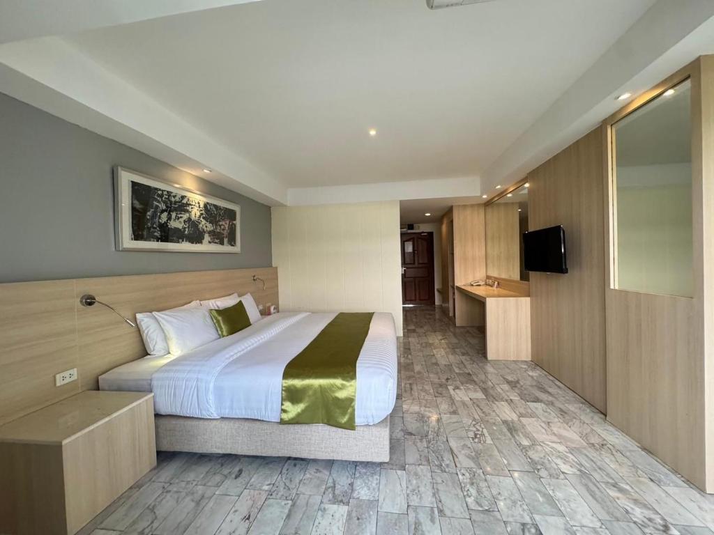 A large-bed room with a wall-mounted television, desk, and generous tiled walkway.