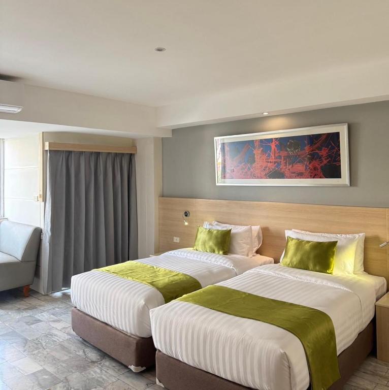 A twin room with two beds, a sofa, curtains, and framed artwork.