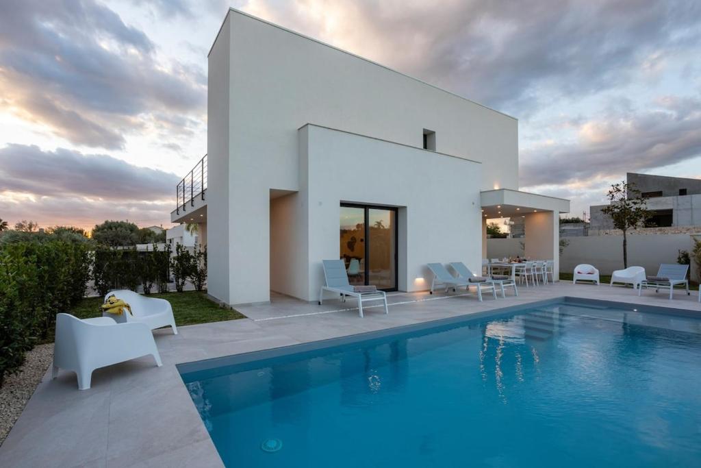 une villa avec piscine devant une maison dans l'établissement Villa Nerissa - IsulaTravel, à Pozzallo