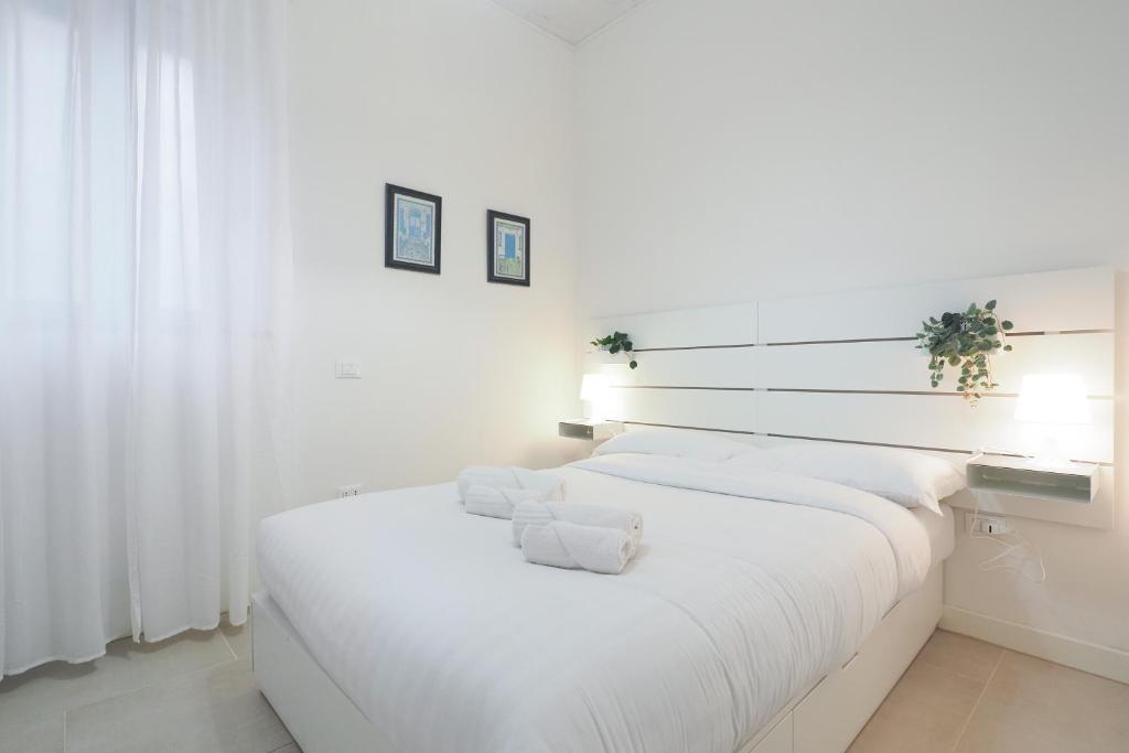 a white bedroom with a large bed with white sheets at PrimoPiano - Sant' Arnaldo in Milan