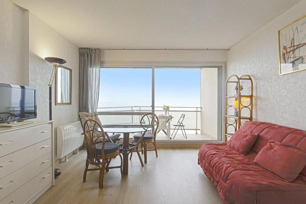 un salon avec un canapé rouge et une table avec des chaises dans l'établissement Studio Croskey - Welkeys, à Biarritz