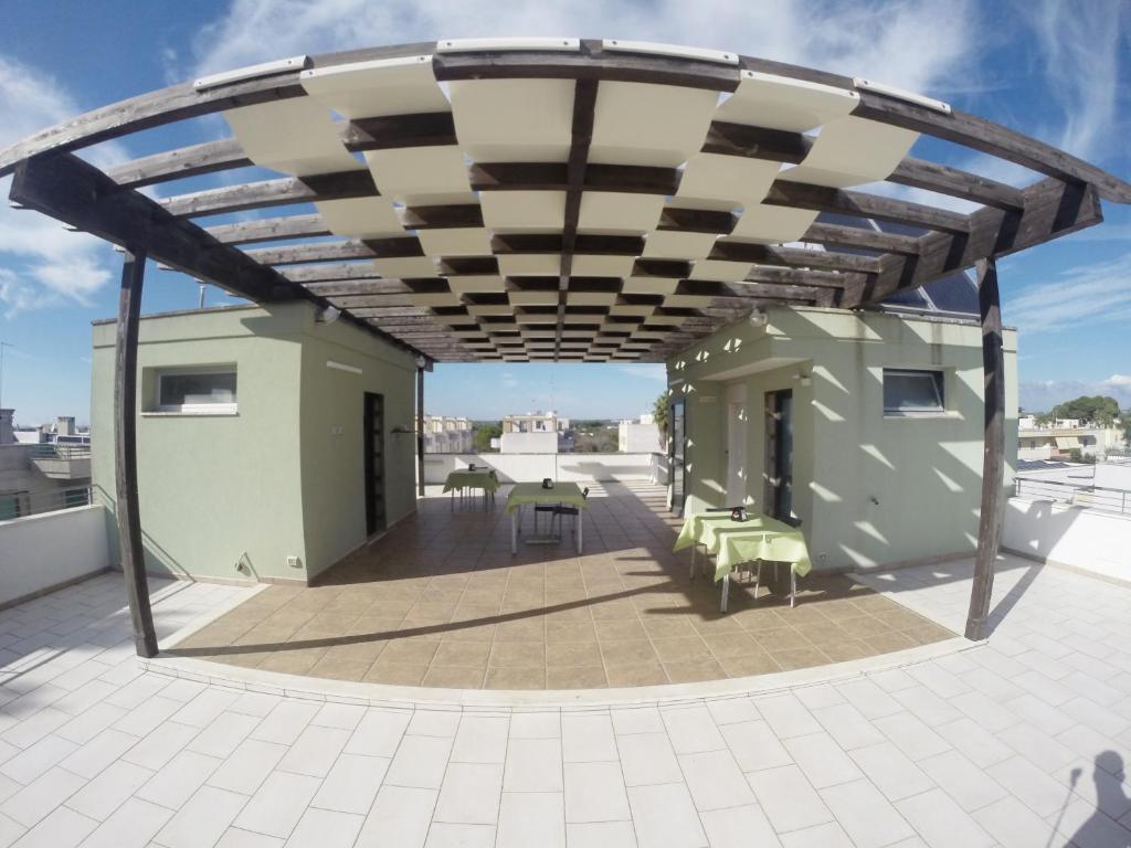 una terrazza sul tetto con tenda da sole, tavoli e sedie di B&B Via Gallipoli ad Alezio