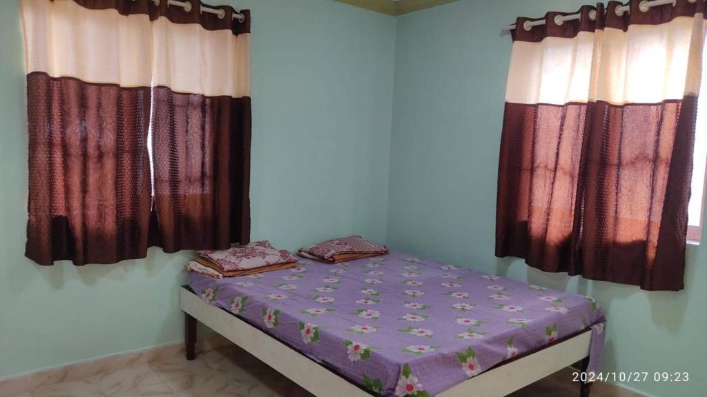 Aakshi Wanderlust Homestay في عليباج: سرير صغير في غرفة بها نافذتين