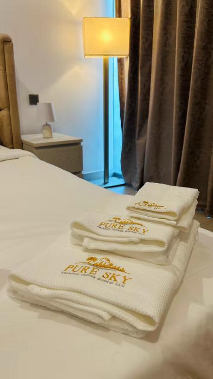 three white towels sitting on top of a bed at MontRose residence Tower A 1BR Apartment in Dubai