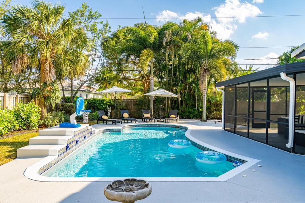 a swimming pool in a yard with palm trees at Villa Heated Pool, Arcade games 5 min Beach in Pompano Beach