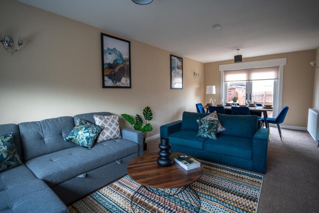 Una sala de estar con dos sofás azules y una mesa. en Skye House, en Grangemouth