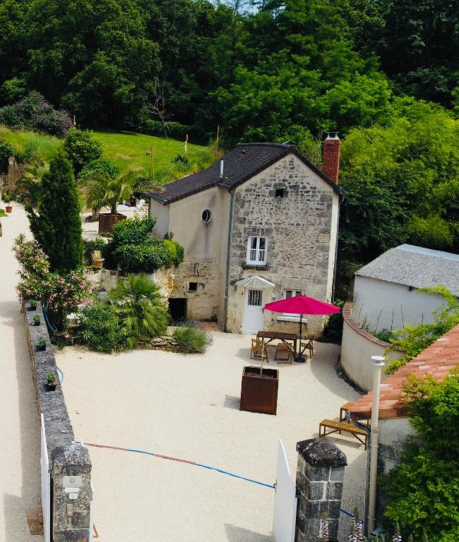 - un bâtiment en pierre avec une table et un parasol rose dans l'établissement Gîte - petite maison proche du Futuroscope, à Beaumont