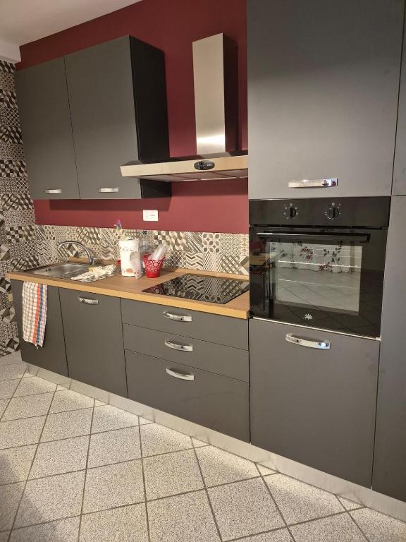a kitchen with gray cabinets and a stove at La Finestra Rossa in Venturina Terme