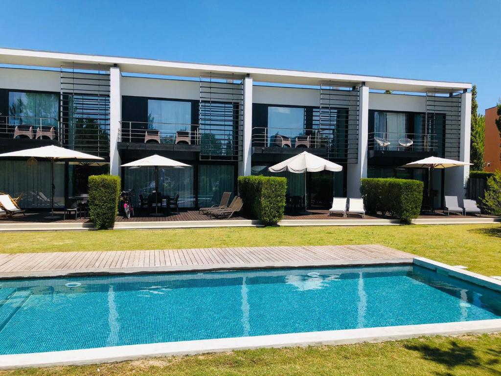 a house with a swimming pool in front of a building at Tróia Beach Pool & Golf in Grândola