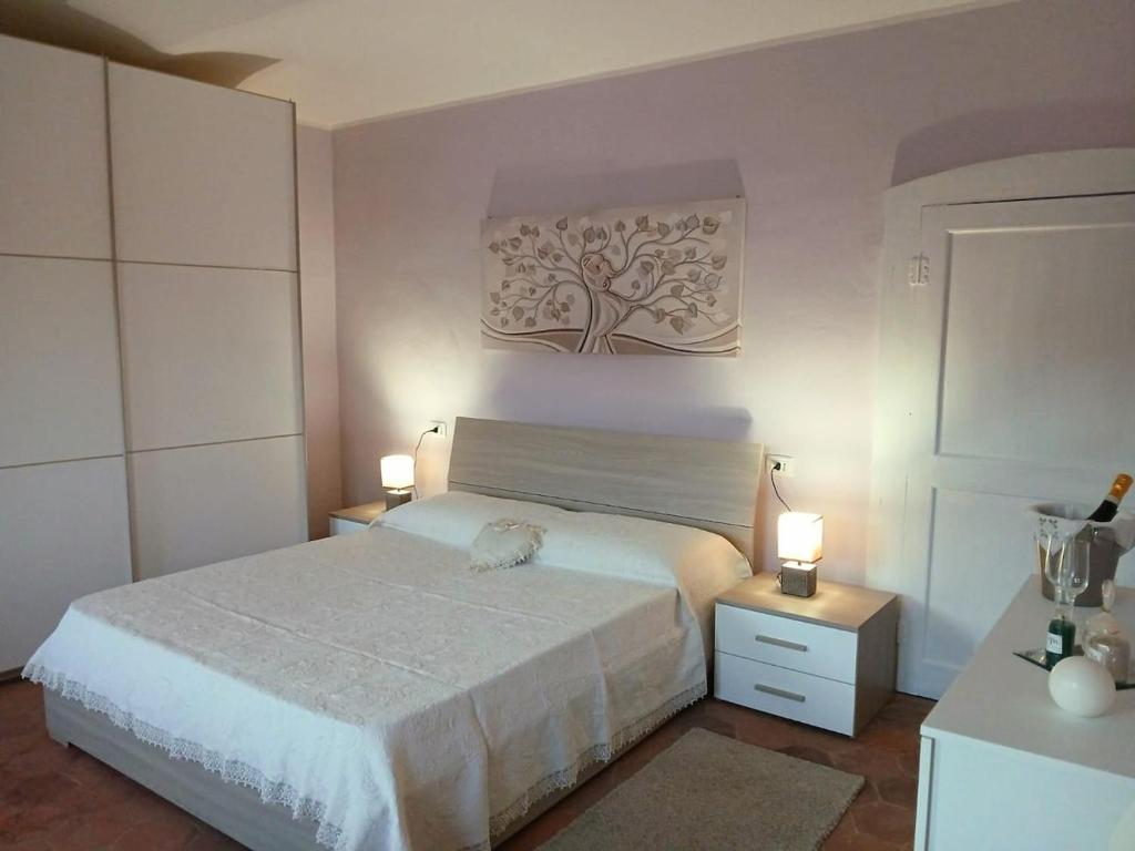 Un dormitorio con una cama blanca y dos mesitas de noche. en Casa Teresina Country House, en Alfiano Natta