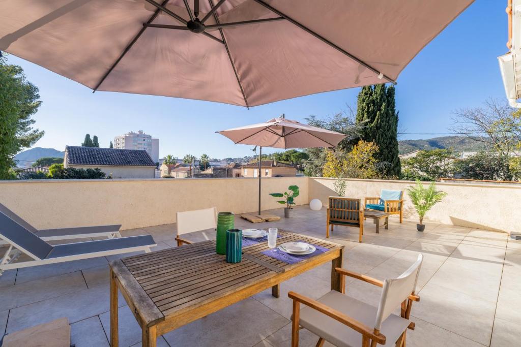 un patio avec une table, des chaises et un parasol dans l'établissement Le Lamartine - Appt climatisé proche du port, à La Ciotat
