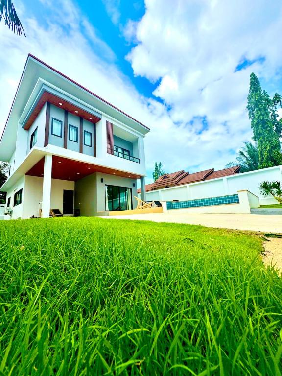 a house with a green lawn in front of it at Luna villa Chaweng Samui in Nathon Bay