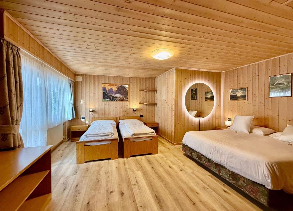 a bedroom with two beds in a wooden room at B&B Family Accommodation Canazei BIKE FRIENDLY in Canazei