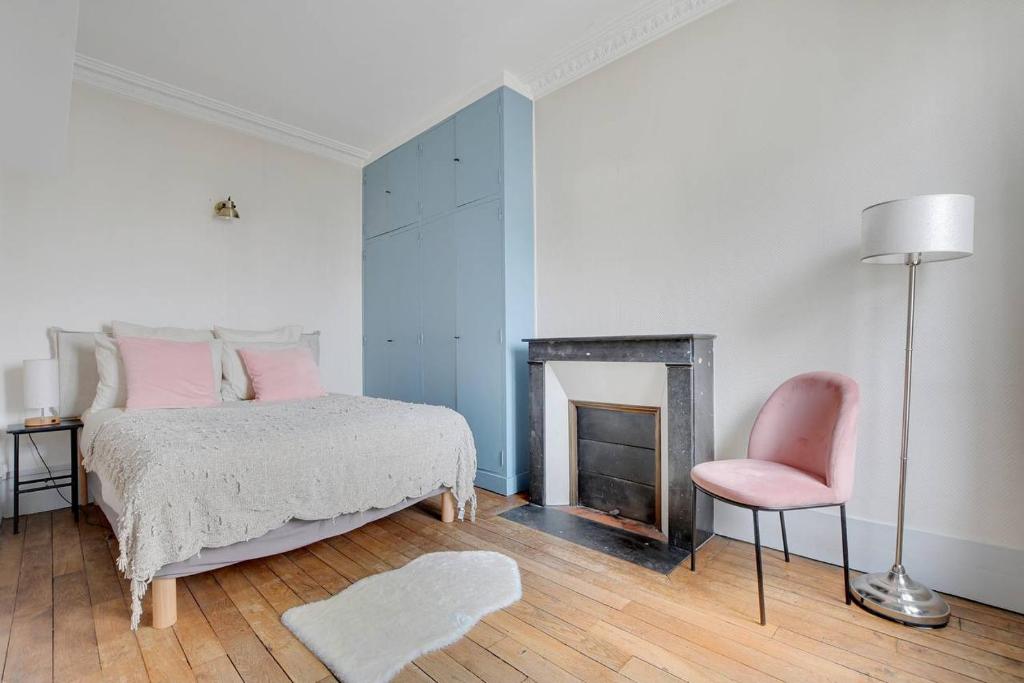 - une chambre avec un lit, une chaise et une cheminée dans l'établissement Tour Eiffel - Saint Dominique - Invalides, à Paris