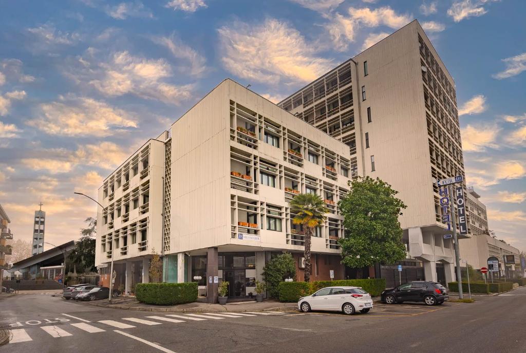 duży biały budynek z samochodem zaparkowanym przed nim w obiekcie iH Hotels Milano Eur - Trezzano sul Naviglio w mieście Trezzano sul Naviglio