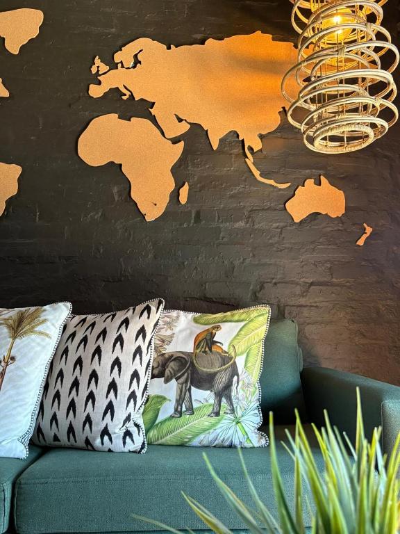 a couch with pillows and a map on a wall at Eccentric Heritage Paradise Simon's Town in Simonʼs Town