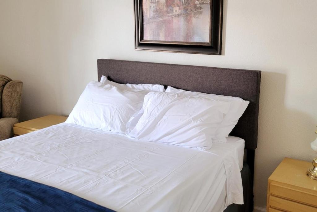 un letto con lenzuola e cuscini bianchi in una camera da letto di The Link Vintage Motel #8 a Lovelock