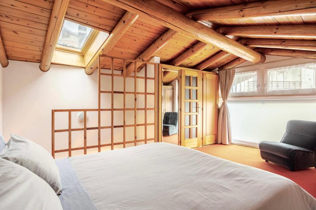a bedroom with a white bed and a chair at Casa al Vicolo [vicino al Lago di Garda] in Cavedine