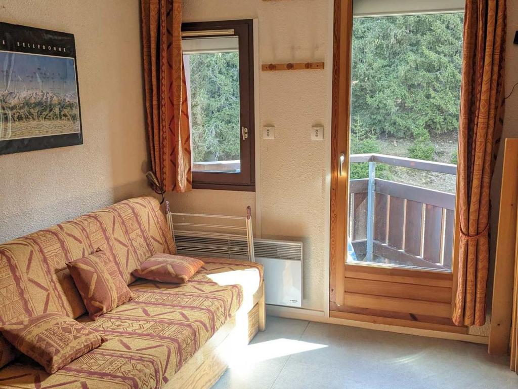 a living room with a couch in front of a window at Studio cosy au pied des pistes avec balcon, 3 couchages - FR-1-557-58 in Les Adrets