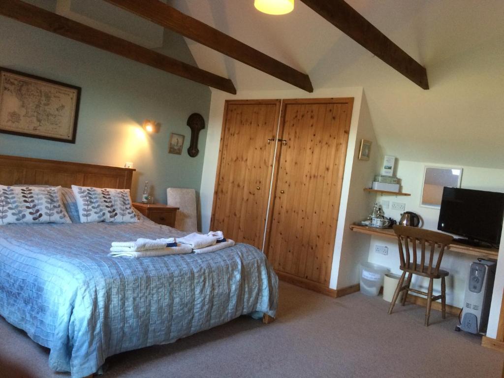 a bedroom with a bed and a desk and a television at Knockaloe Beg Farm in Patrick