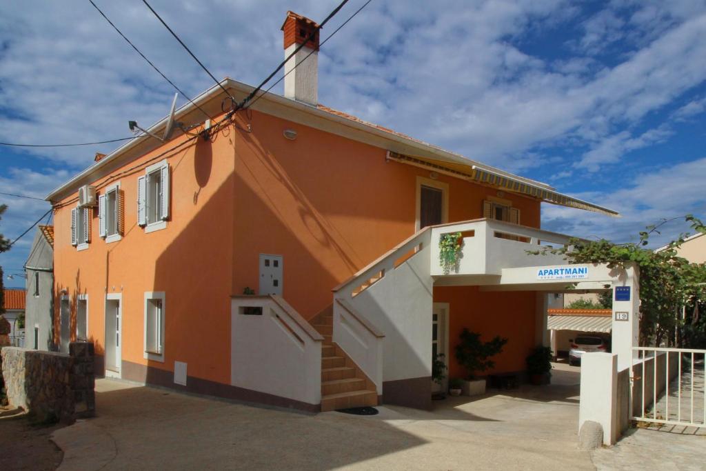 a orange house with a white door in front of it at Apartments Meri in Punat
