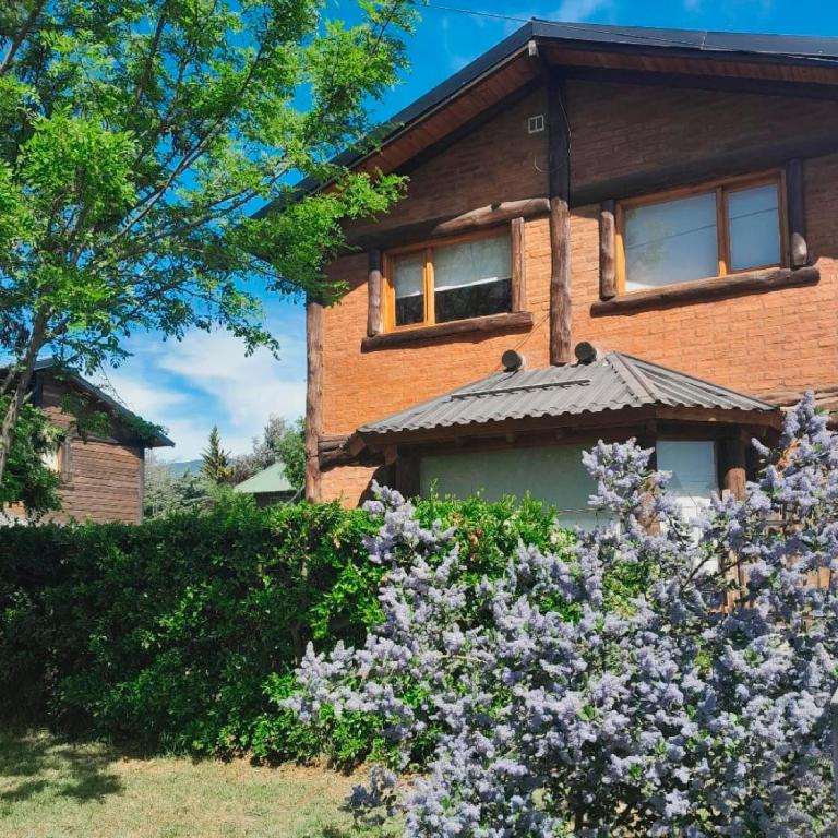 a house with purple flowers in front of it at Acacias in El Bolsón