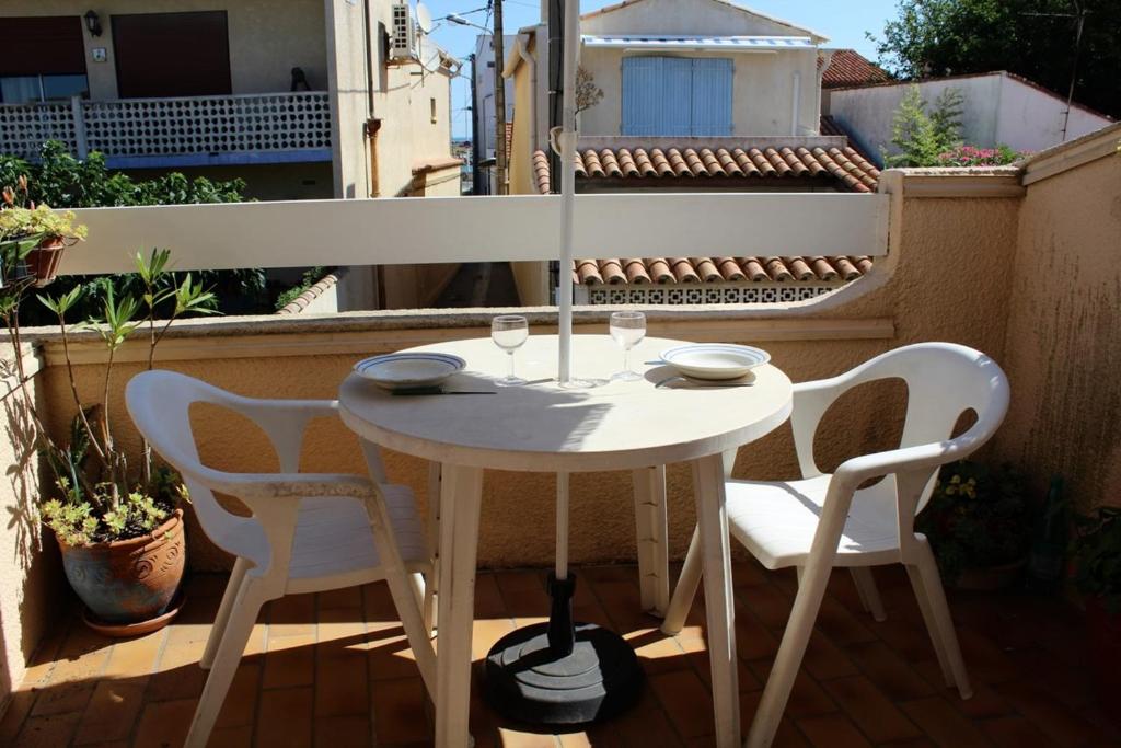 une table blanche et des chaises sur un balcon dans l'établissement PN000-201 Maison Studio mezz 2 couchages PORT LA NOUVELLE, à Port-la-Nouvelle