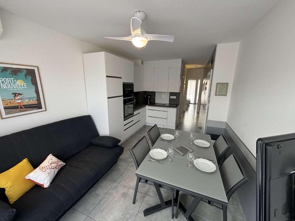 un salon avec un canapé noir et une table dans l'établissement Appartement deux pièces Port la Nouvelle PN015-017, à Port-la-Nouvelle